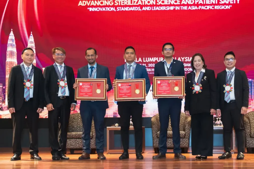Azrul Akmal Saharudin receiving a framed certificate of appreciation on stage from APSS 2026 summit dignitaries in Kuala Lumpur.