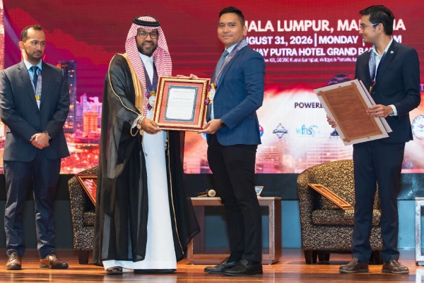 Azrul Akmal receiving a framed certificate of appreciation on stage from APSS 2026 summit dignitaries in Kuala Lumpur.